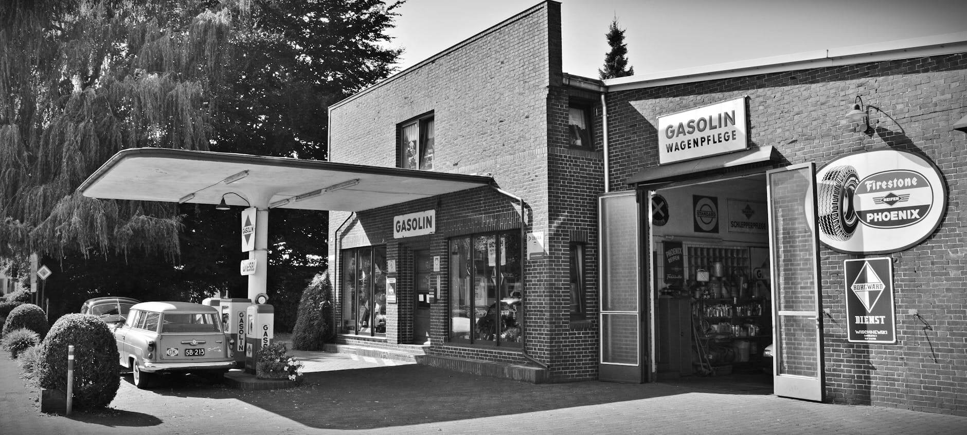 gray scale photo of a sedan parked infront of store